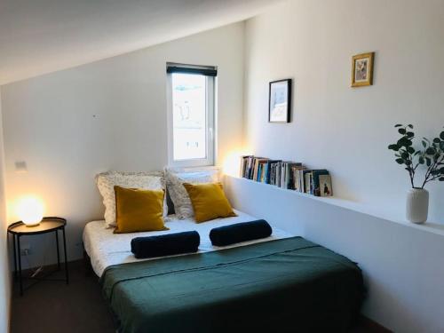 a room with a bed with yellow pillows and a book shelf at La Maison Racine 2 - Joli duplex sous les toits in Avignon