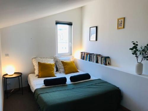 une chambre avec un lit avec des oreillers jaunes et une étagère dans l'établissement Marie - La Maison Racine 2 - Joli duplex sous les toits, à Avignon