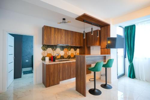 una cocina con armarios de madera y taburetes de bar verde en Green Luxury Apartament en Mamaia-Sat