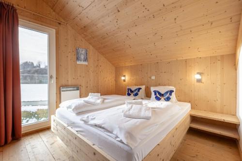a large bed in a room with a large window at Feriendorf Murau by ALPS RESORTS in Murau