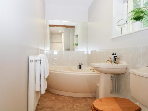 a white bathroom with a tub and a sink at Hungers Cottage in Petworth