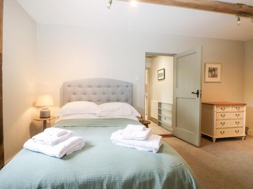a bedroom with a large bed with towels on it at Hungers Cottage in Petworth