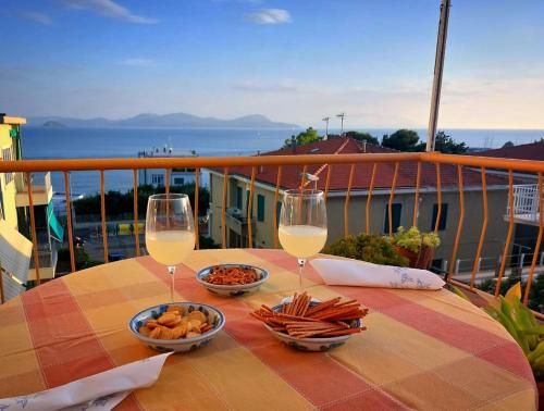 a table with two glasses of wine and snacks on a balcony at Il Balcone sull'Elba in Piombino