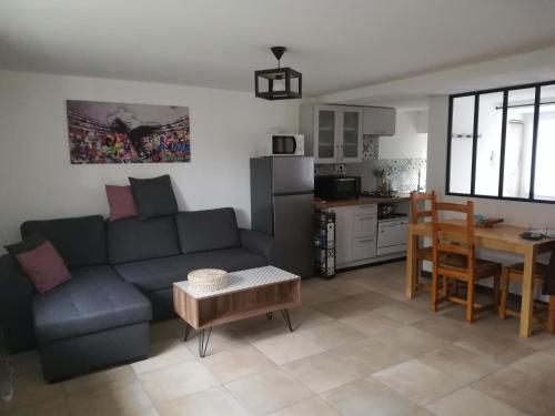 een woonkamer met een bank en een tafel en een keuken bij Gîte indépendant neuf, idéal vacances nature au calme, proche rivières, N147 & Civaux in Mazerolles