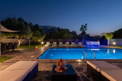 a swimming pool at night with a table and a drink on a table sidx sidx at Sun Dream Villa in Ialyssos