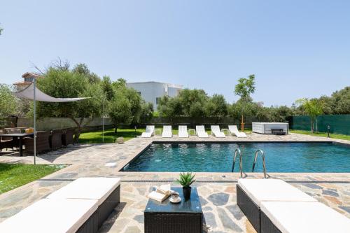 a swimming pool with chairs and a table in a yard at Sun Dream Villa in Ialyssos