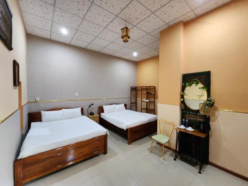a room with two beds and a table and a chair at Tầm Quên Homestay in Tây Ninh