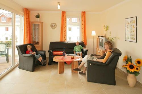 deux femmes et deux enfants assis sur des chaises dans un salon dans l'établissement Villa Sonnenstrand II, à Bansin