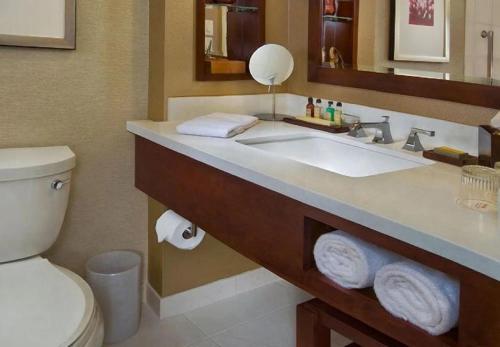 W łazience znajduje się umywalka, toaleta i lustro. w obiekcie Marriott Louisville East w mieście Louisville