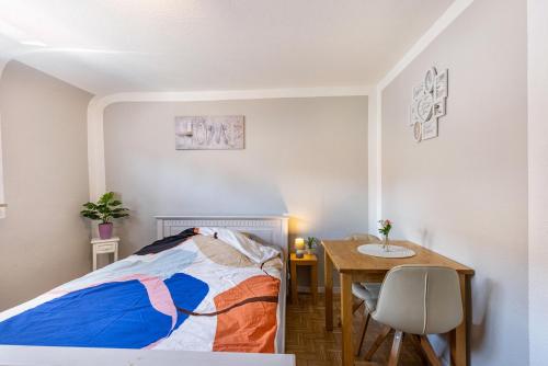 a bedroom with a bed and a table and a desk at Baumelt Ferienwohnung in Hechingen