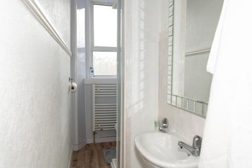 ein weißes Badezimmer mit einem Waschbecken und einem Spiegel in der Unterkunft Centrally located 1 bed flat with furnishings & white goods. in Gourock