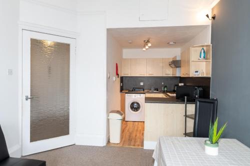 a kitchen with a door open to a kitchen with a washing machine at Centrally located 1 bed flat with furnishings & white goods. in Gourock
