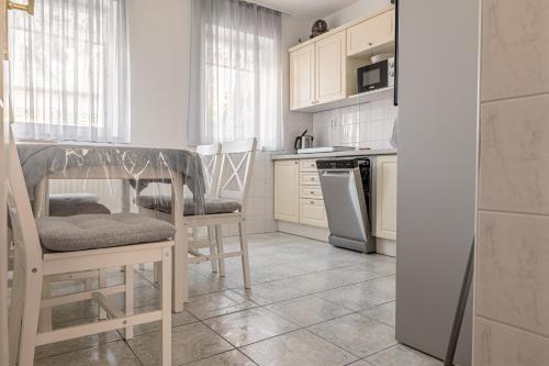 cocina con armarios blancos, mesa y sillas en Barát Vendégház - Cosy Guesthouse - Teljes ház privát udvarral - 4 szoba, 2 fürdő, en Szeged