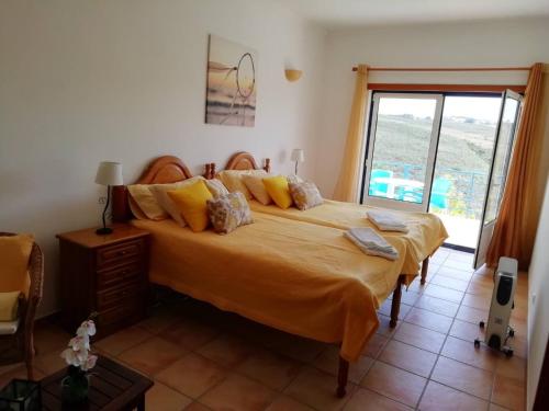 1 dormitorio con 1 cama grande con sábanas amarillas y ventana en Brisamar, en Aljezur
