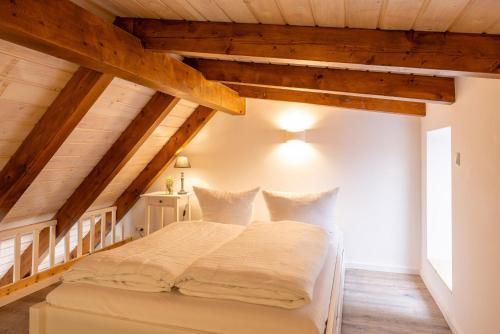 Una cama blanca en una habitación con techos de madera. en Ferienwohnungen Wildau am Werbellinsee, en Schorfheide