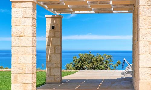 un arco de piedra con el océano en el fondo en Vista Mare Villas Heated Pool, en Georgioupoli