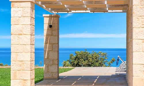 un arco in pietra con l'oceano sullo sfondo di Vista Mare Villas Heated Pool a Georgioupoli