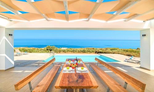 a dining room with a table and a swimming pool at Vista Mare Villas Heated Pool in Georgioupoli