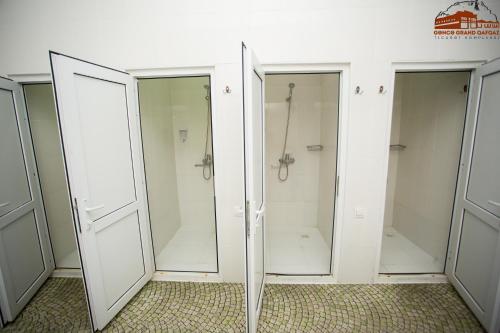 a group of four glass showers in a bathroom at Grand Qafqaz Hostel in Ganja