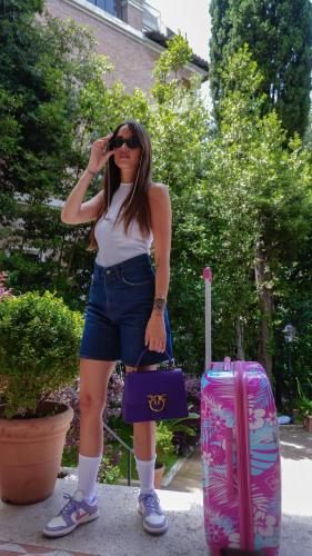 a woman talking on a cell phone next to a suitcase at Mangili Garden Hotel in Rome
