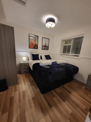 Lovely 2-Bed Apartment in Grays في South Ockendon: غرفة نوم بسرير كبير وارضية خشبية