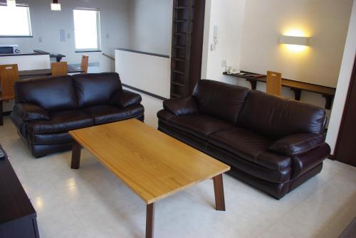 a living room with two leather couches and a coffee table at Chalet Fuyuri in Furano