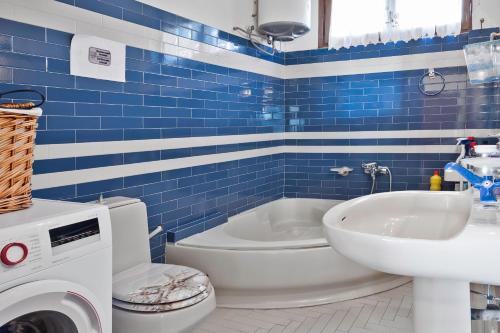a blue tiled bathroom with a toilet and a sink at Alex Spiti in Keratokampos