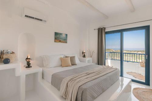 a white bedroom with a bed and a balcony at Villa Giasemi-Iris sunset villas in Lépedha