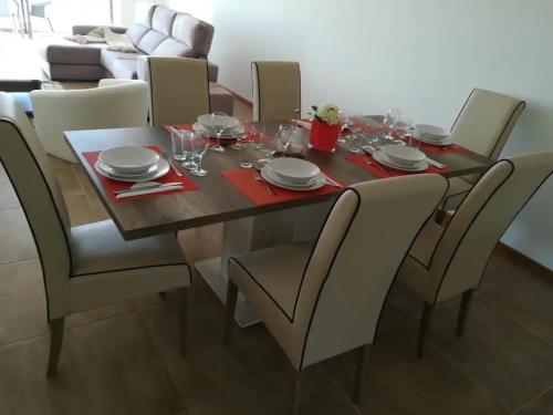 a dining room table and chairs with plates and glasses at Pôr do Sol in Aljezur