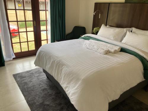 uma cama grande com lençóis brancos e almofadas num quarto em Edenvale corner em Edenvale