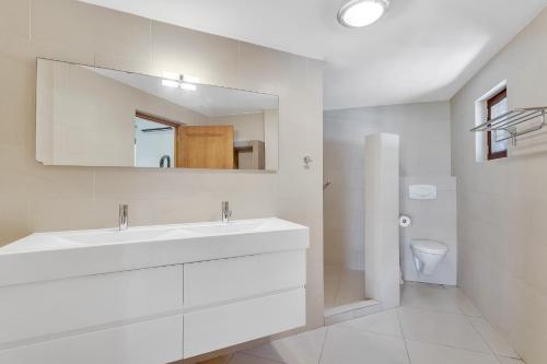 uma casa de banho branca com um lavatório e um espelho em Bonaire Apartment em Kralendijk