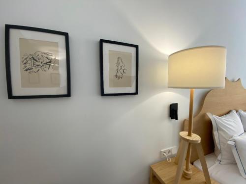 a bedroom with two framed drawings on the wall and a lamp at Hotel Maïa in Ciutadella
