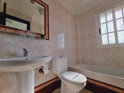 a bathroom with a toilet and a sink and a tub at Victoria Hotel in Matalascañas