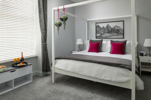 a bedroom with a canopy bed with pink pillows at Nythfa in Llanrwst