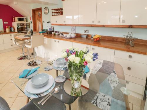 a kitchen with a table with a vase of flowers on it at Coast Cottage in Bamburgh