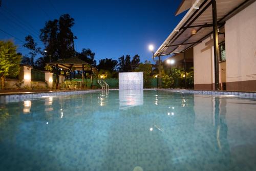 an empty swimming pool in front of a building at night at The Royal Villa in Panchgani