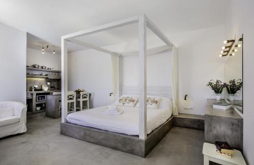a bedroom with a white canopy bed and a kitchen at Lindian Pearl in Lindos