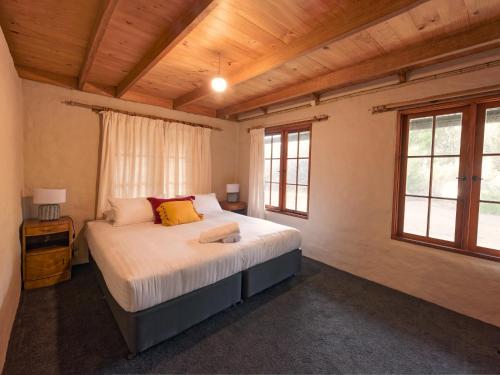 1 dormitorio con 1 cama grande en una habitación con ventanas en Cloudy Creek Cottage, en South Bruny