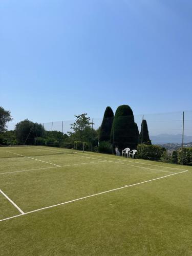 a tennis court with two white chairs on it at Garden sea view - Victoria - Le Cannet in Le Cannet