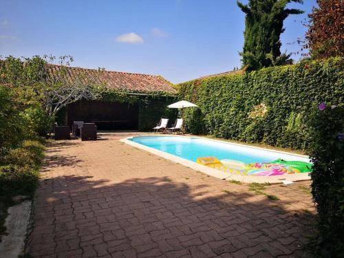 una piscina con sillas y un patio con sombrilla en Belle maison de maître à 200 m du Canal du midi, en Castelsarrasin