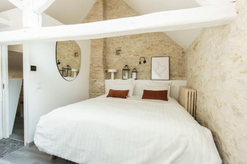 1 dormitorio con 1 cama blanca en una pared de ladrillo en My Home Prestige / SPA Privatif en Châteauroux