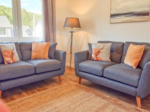 a living room with two blue couches and a lamp at 4 Ben Avon in Aviemore