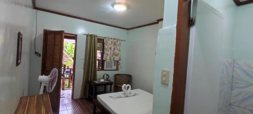 Habitación con mesa blanca y ventana en ALFA Garden Lodge, en El Nido