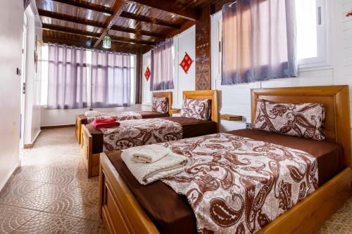 a bedroom with two beds in a room with windows at The Rina Hostel in Agadir