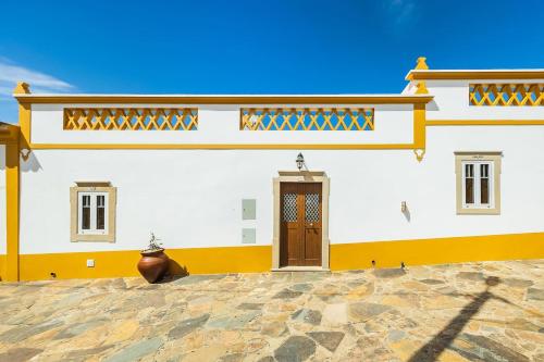 a white and yellow building with a brown door at Casa do Forno (Vale Luis Neto-Retiro do Caldeirão) in Loulé