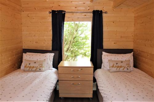 two twin beds in a cabin with a window at Inviting 3-Bedroom Lodge in Ashton Under Hill in Evesham