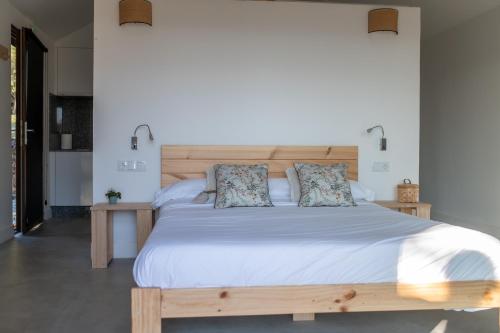 a bedroom with a large white bed with a wooden headboard at O rincón dos Sentidos in Cenlle