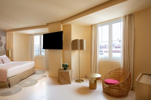 a bedroom with a bed and a chair and a window at Room Mate Macarena, Madrid Gran Vía in Madrid