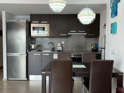 a kitchen with stainless steel appliances and a table with chairs at BLAU Apartamento frente a los canales y las puestas de sol de Roses in Roses
