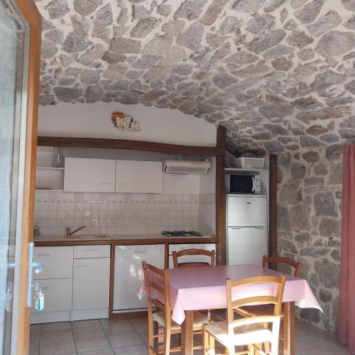 - une cuisine avec une table et un mur en pierre dans l'établissement Gîte le Petit Riou, à Sainte-Marguerite-Lafigère